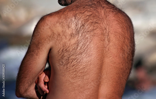man with a very hairy back standing outside by a river on a hot summer day