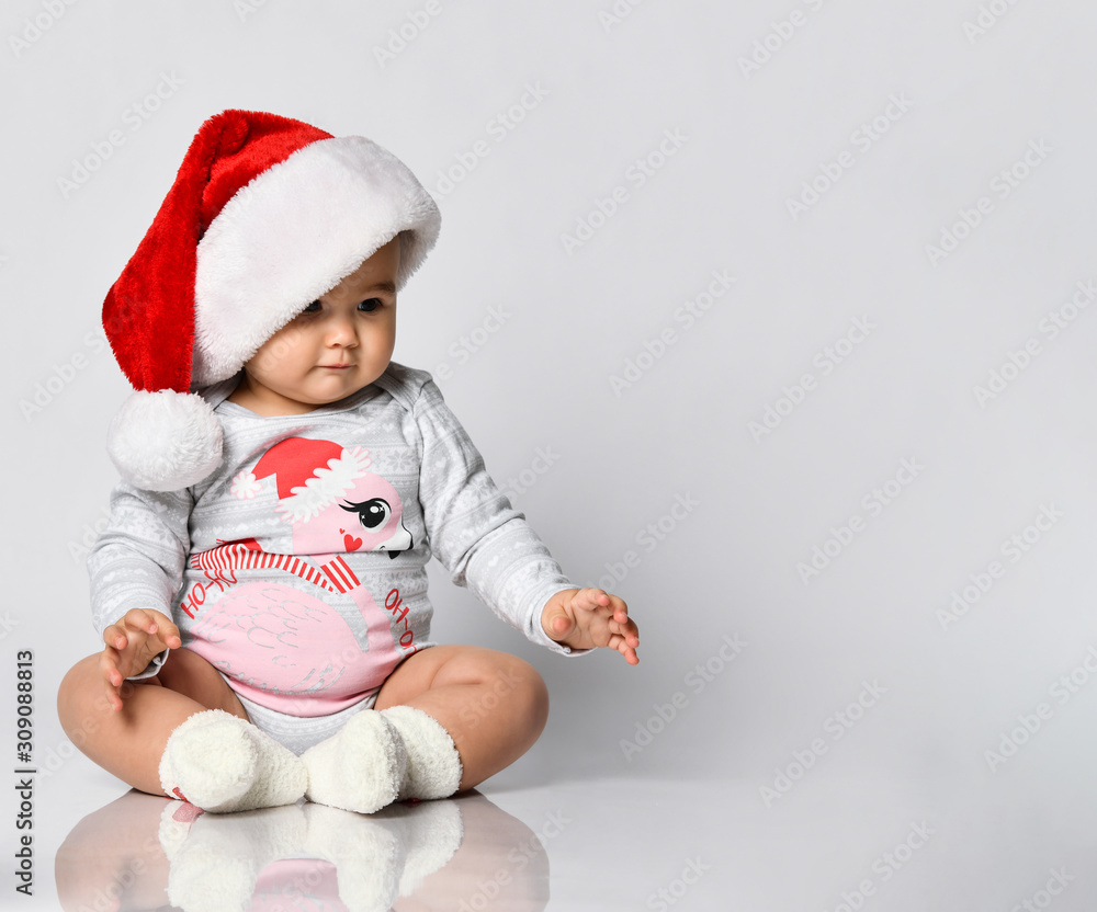 Smiling baby toddler playing with christmas tree red glass balls rolling on the floor Smiling baby toddler playing with christmas tree red glass balls rolling on the floor