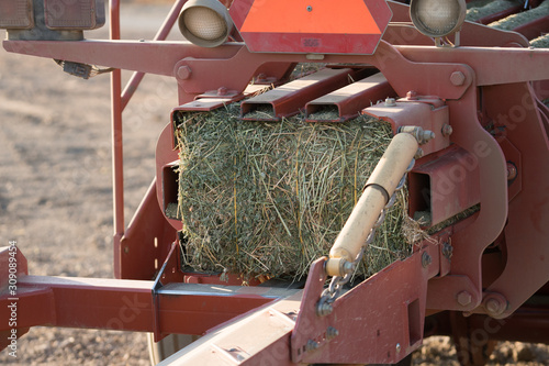Photography red hay alfalfa bailing tractor with bail finished. 