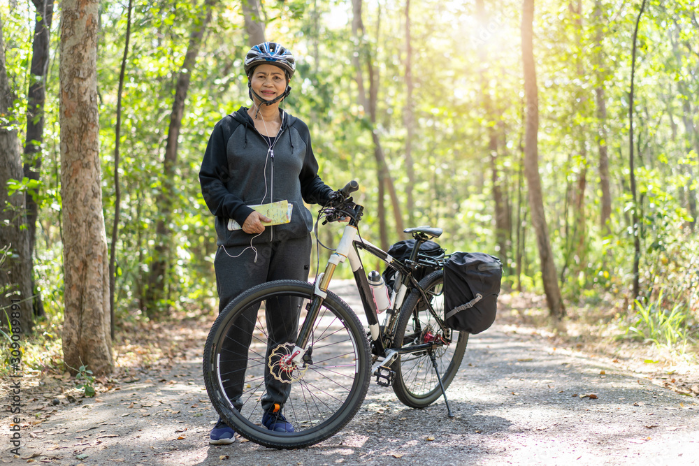 Fototapeta premium Senior asian woman riding bikes in park with hold map on trip