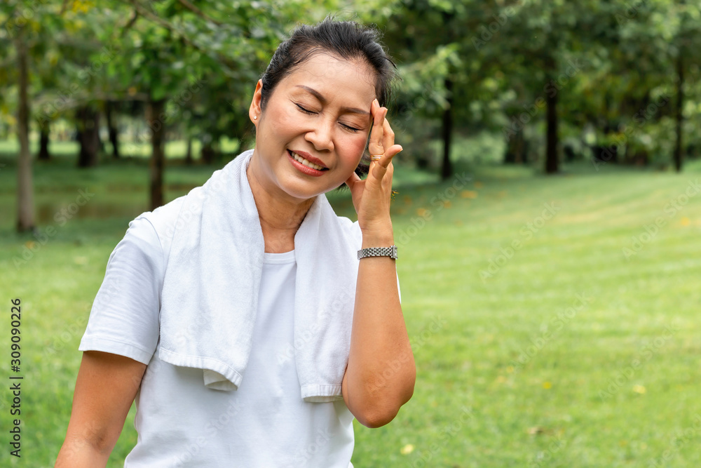 In the morning.Senior woman Asian headache during exercise at the park. In the morning.Senior woman Asian headache during exercise at the park.