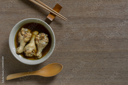 top view of chicken drumette soup in a ceramic bowl on wooden table. asian style food concept.