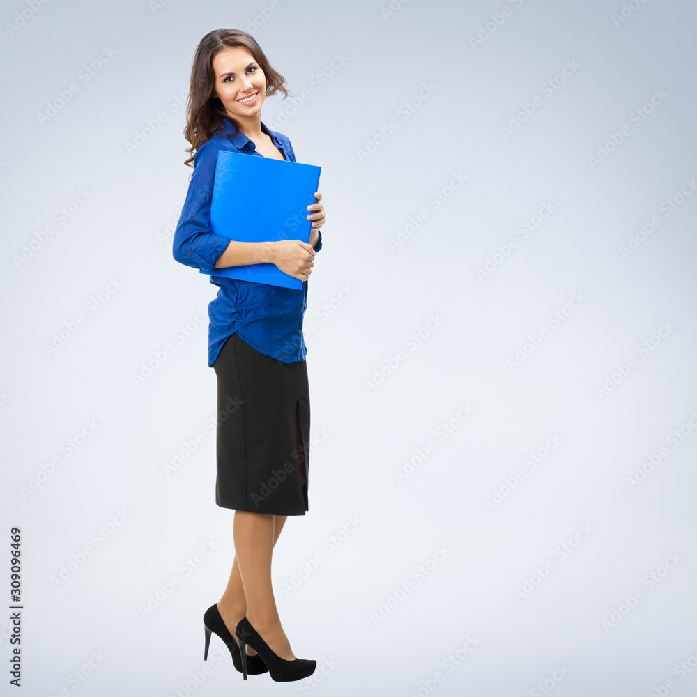 Full body portrait of young smiling businesswoman in corporate style with blue folder, with blank copy space area for slogan or text Full body portrait of young smiling businesswoman in corporate style with blue folder, with blank copy space area for slogan or text