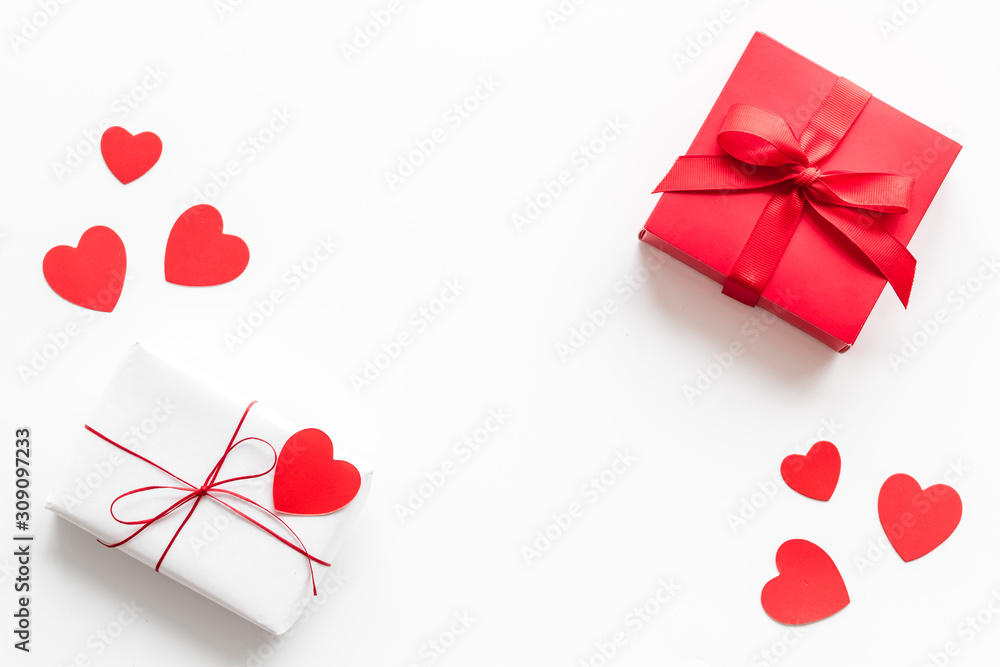 Present to a lover on Valentine's Day. Gift boxes near paper hearts on white background top-down frame copy space