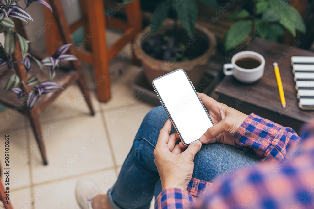 Obraz premium Mockup image blank white screen cell phone.men hand holding texting using mobile on desk at home office.background empty space for advertise text.people contact marketing business and technology 