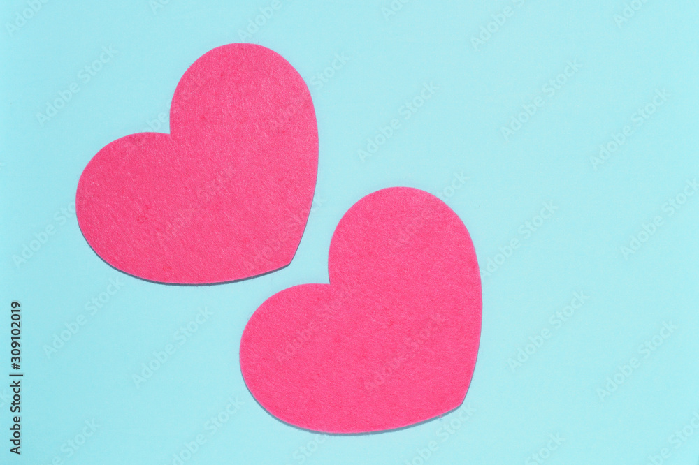 Obraz premium Two pink hearts on a blue background close-up. Greeting card with copy space. Flat lay minimal concept. Valentine's Day background