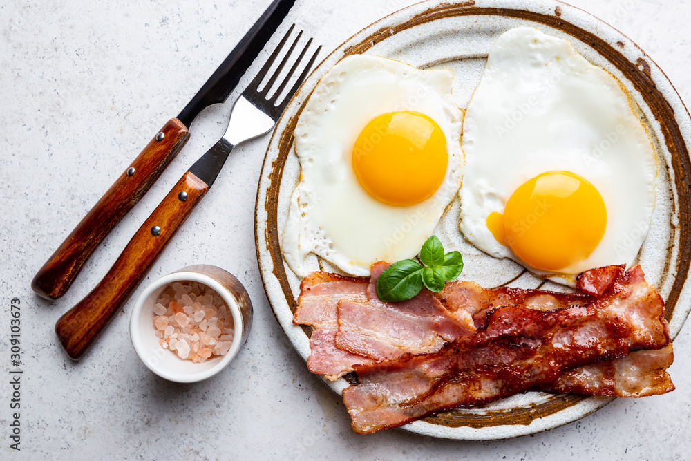 Fried eggs and bacon for breakfast on a plate, top view, copyspace - obrazy, fototapety, plakaty 