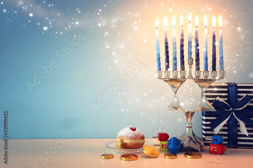 religion image of jewish holiday Hanukkah with menorah (traditional candelabra), spinning top and doughnut over wooden background
