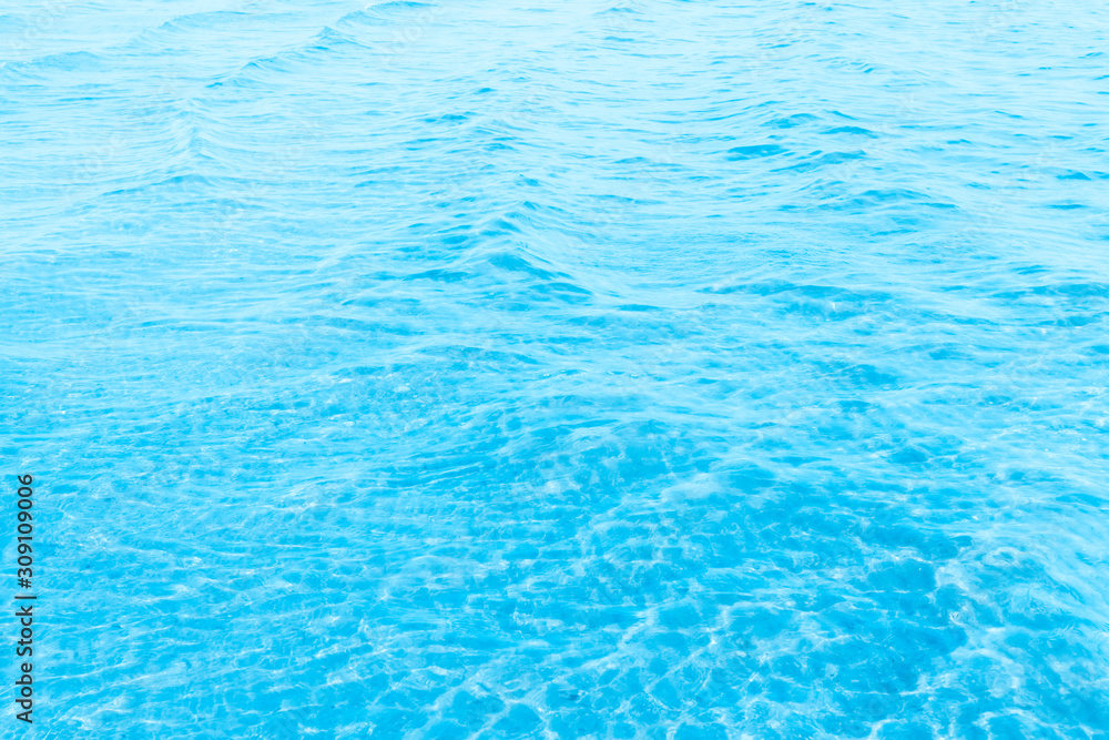 Blue transparent sea water near the beach texture background. clear water surface with slight waves and glare on a sunny day. sea ​​vacation