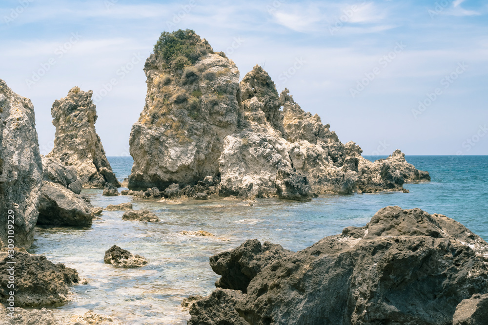 Sea rocks in tidal aves along Ionian sea coast in Paleokastritsa resort in June. Corfu Island, Greece