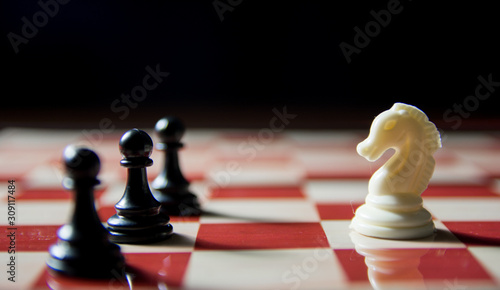 Close up shot White knight vs 3 black pawns. Knight vs pawns in chess