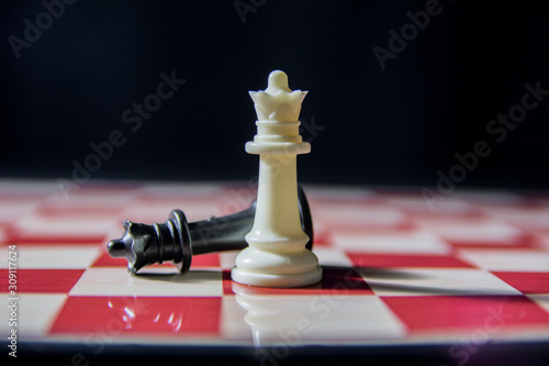 Contrast shot on chess board. White queen in front of black army of pawns, rook and bishop
