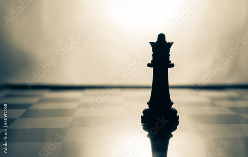 Silhouette shot of black queen on chess board with vintage look
