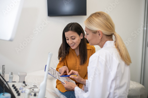 Blond doctor in white robe showing ultrasound results to patient