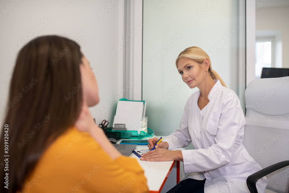 Blond doctor in white robe telling the examination results to patient Blond doctor in white robe telling the examination results to patient