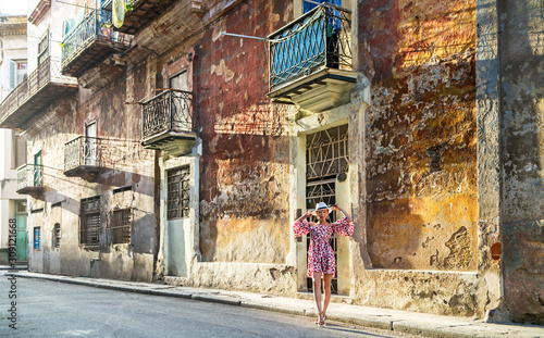 Young woman in a colored dress on a city street in the sunshine 