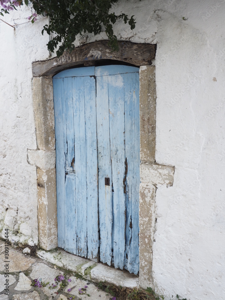 old blue wooden door in white wall greek village