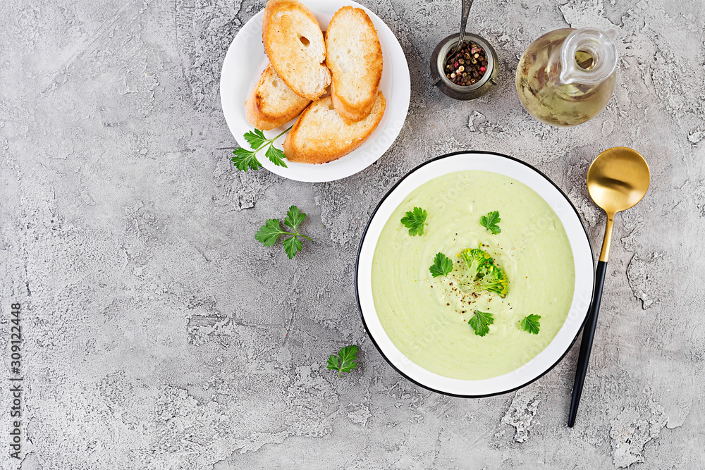 Homemade broccoli cream soup with croutons in white bowl on grey background. Healthy vegetarian food. Vegan menu. Top view, copy space Homemade broccoli cream soup with croutons in white bowl on grey background. Healthy vegetarian food. Vegan menu. Top view, copy space