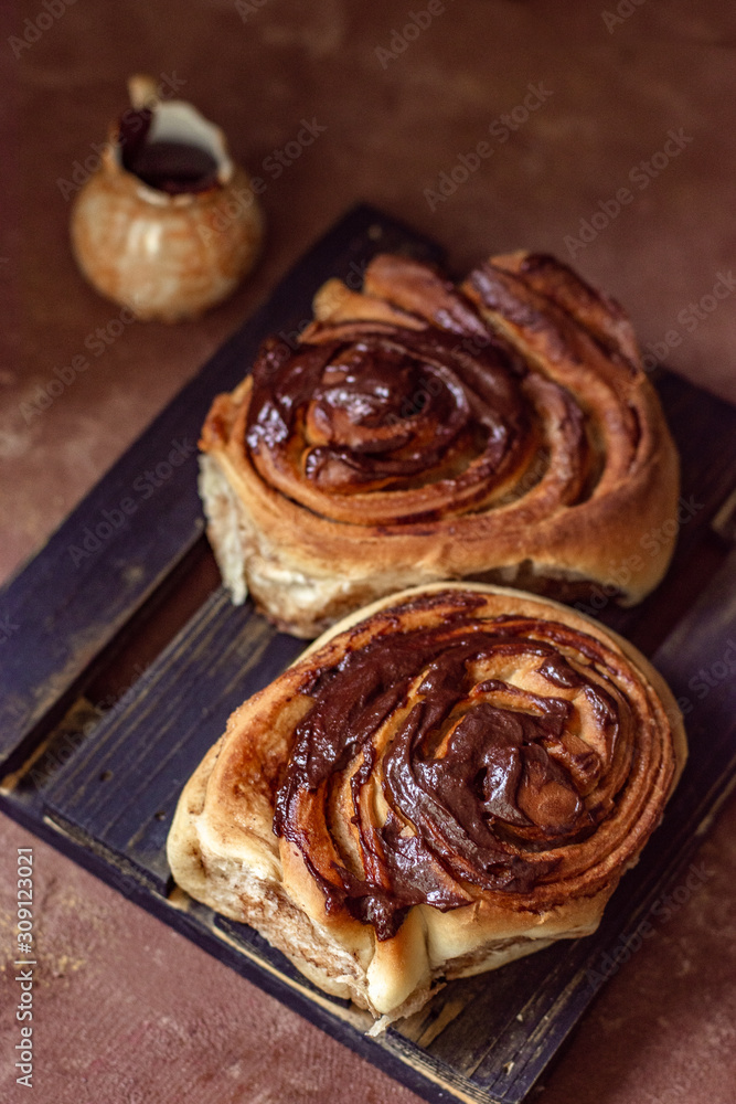 Brioche with chocolate on a wooden stand and a sauce-boat in rustic style Brioche with chocolate on a wooden stand and a sauce-boat in rustic style