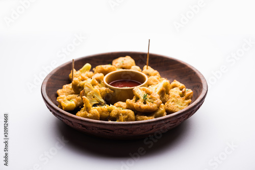 Gobi pakora or Phoolgobi pakoda made using fresh cauliflower dipped chickpea batter and then fried in oil. served with tomato ketchup and mint chutney. selective focus