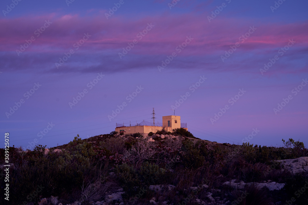 water tank on top of a hill with a blue sky and pink clouds