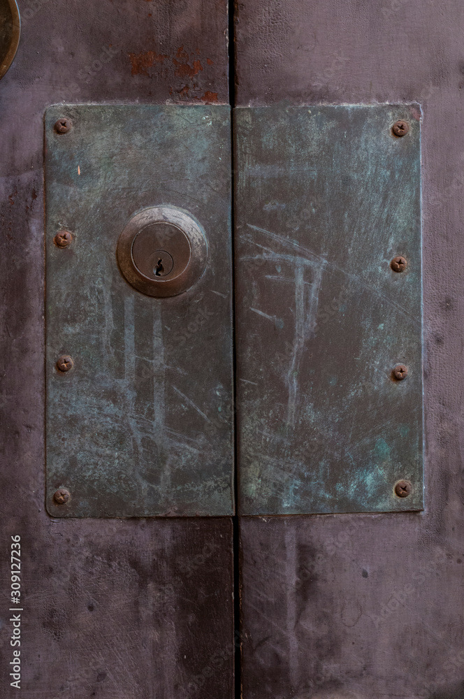 Old door lock with large metal plate on purple wood door Old door lock with large metal plate on purple wood door