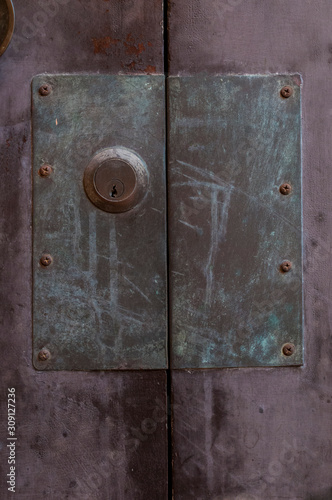 Old door lock with large metal plate on purple wood door