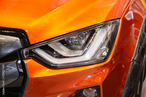 Close up of detail on one of the LED headlights modern and luxury orange car. Select focus.