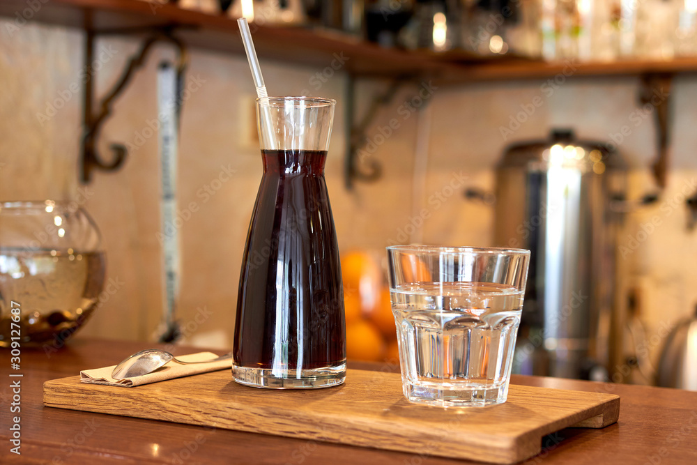 Glass with cold brew coffee and glass with water on a coffee shop counter