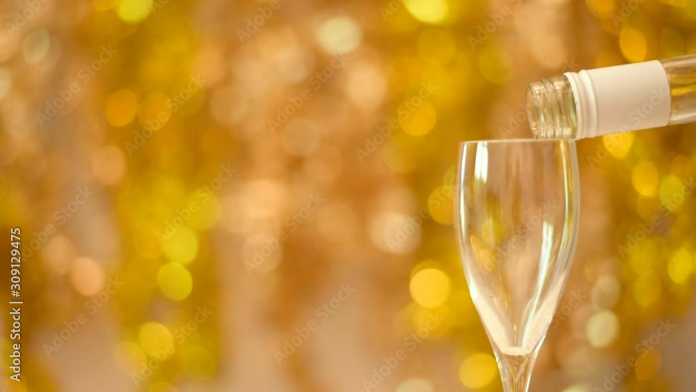 Happy holidays celebrating. One Flute with Sparkling Wine. Pouring Champagne over golden Holiday background Happy holidays celebrating. One Flute with Sparkling Wine. Pouring Champagne over golden Holiday background