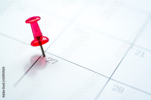 Red push pin on calendar 27th day of the month