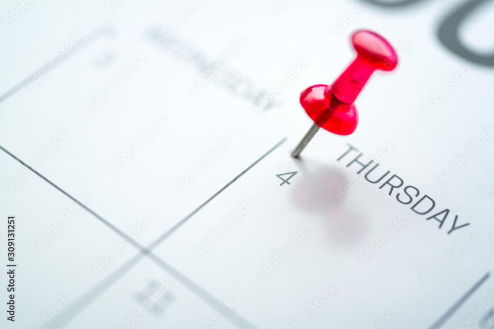 Red push pin on calendar 4th day of the month Red push pin on calendar 4th day of the month