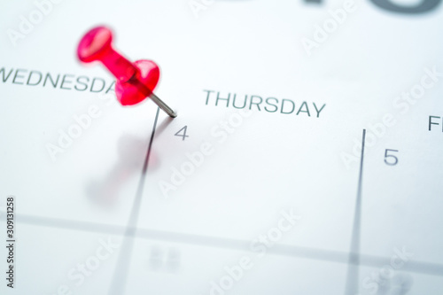 Red push pin on calendar 4th day of the month
