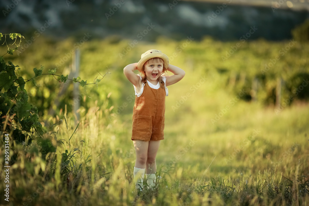 Little girl walking in a field wearing a cowboy hat.
