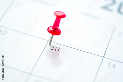 Red push pin on calendar 13th day of the month