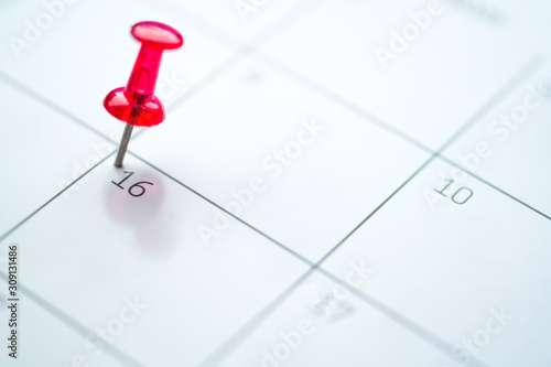 Red push pin on calendar 16th day of the month