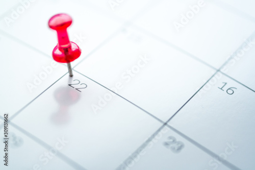 Red push pin on calendar 22nd day of the month