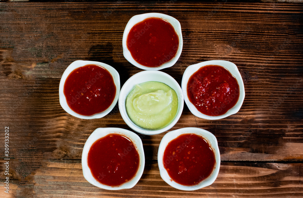 Bowls with guacamole and salsa on the wood background. Top view. Bowls with guacamole and salsa on the wood background. Top view.
