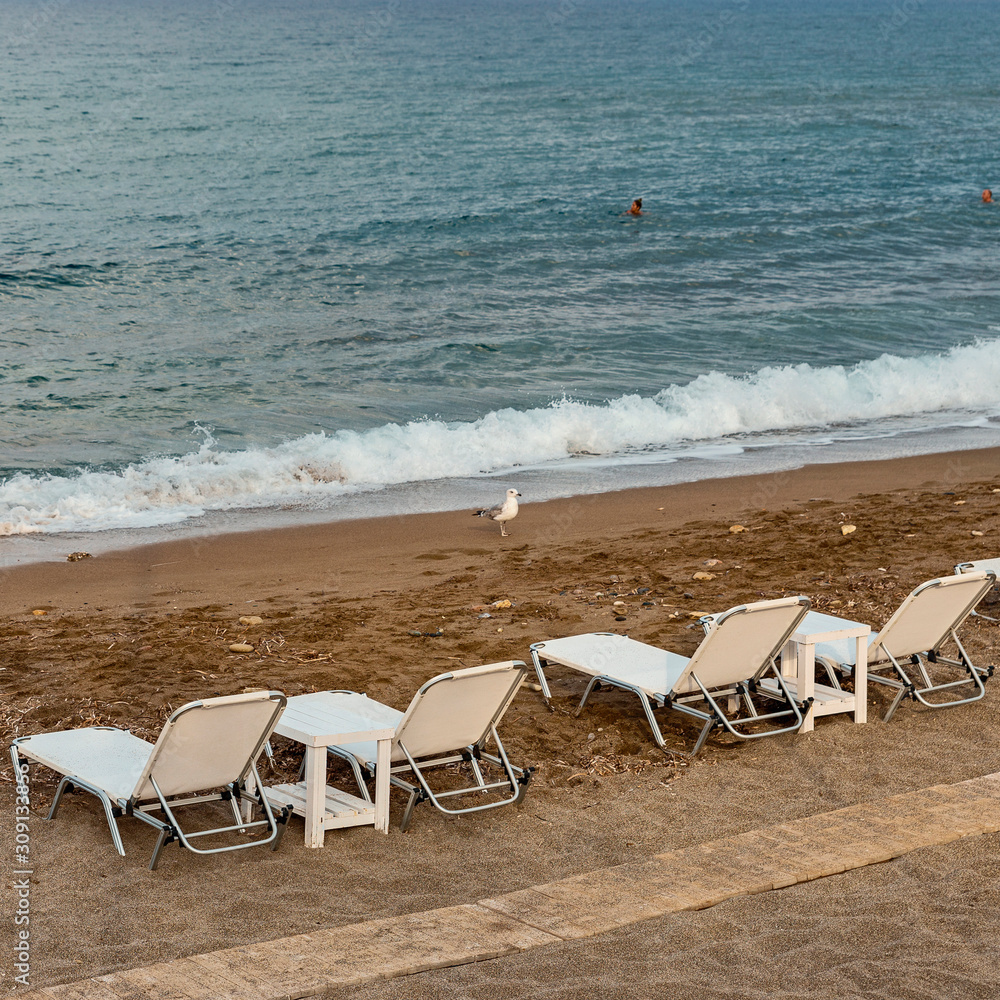 chaise lounges with plastic tables on the sandy beach of the Spanish resort town of Magaluf chaise lounges with plastic tables on the sandy beach of the Spanish resort town of Magaluf