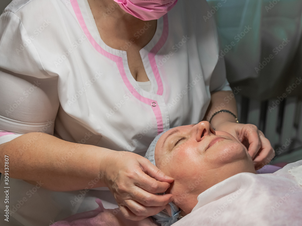 A cosmetic procedure with manual facial massage in a beauty salon is performed for an aged woman. Improving skin turgor, rejuvenation and healing. A cosmetic procedure with manual facial massage in a beauty salon is performed for an aged woman. Improving skin turgor, rejuvenation and healing.