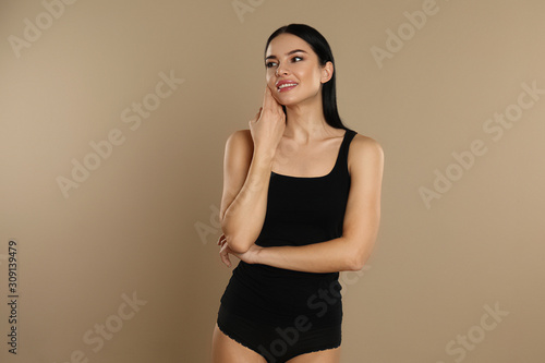 Fototapeta Beautiful young woman in black underwear on beige background