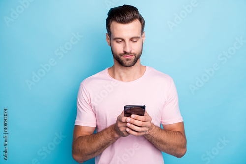 Closeup photo of attractive guy holding telephone hands blogger writing new comments modern person wear casual pink t-shirt isolated blue color background © deagreez