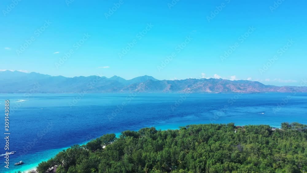 Lush Island In Indonesia - Tropical Paradise Of Green Trees Surrounded By Deep Blue Sea Water Facing The Scenic Mountain Under The Blue Sky - Wide Shot Lush Island In Indonesia - Tropical Paradise Of Green Trees Surrounded By Deep Blue Sea Water Facing The Scenic Mountain Under The Blue Sky - Wide Shot