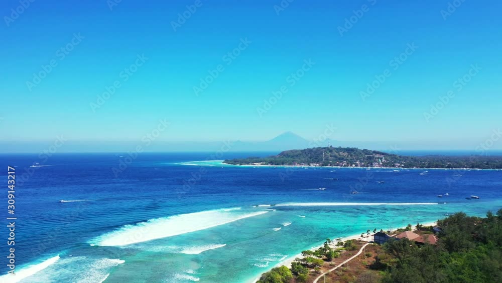Islands In Indonesia - Boats Swiftly Sailing Across The Blue Ocean Water Surrounding The Lush Island With Green Trees Fringed On Its White Sand, Waves Slowly Moving Onto The Shore - Wide Shot Islands In Indonesia - Boats Swiftly Sailing Across The Blue Ocean Water Surrounding The Lush Island With Green Trees Fringed On Its White Sand, Waves Slowly Moving Onto The Shore - Wide Shot