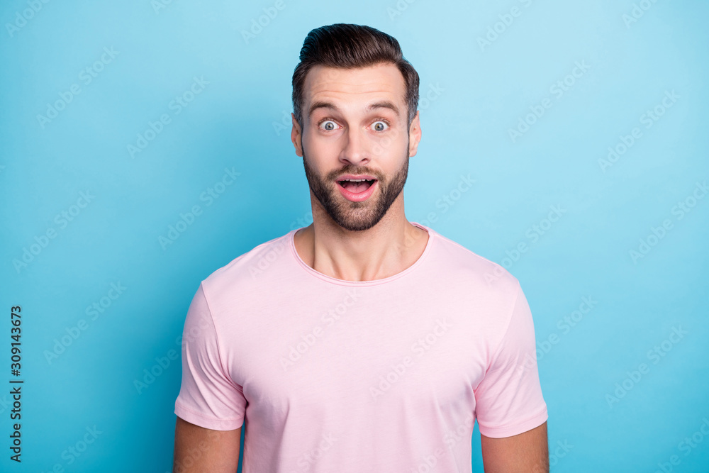 Closeup photo of amazing guy with open mouth not believe eyes astonished unexpected good news wear casual pink t-shirt isolated blue color background Closeup photo of amazing guy with open mouth not believe eyes astonished unexpected good news wear casual pink t-shirt isolated blue color background