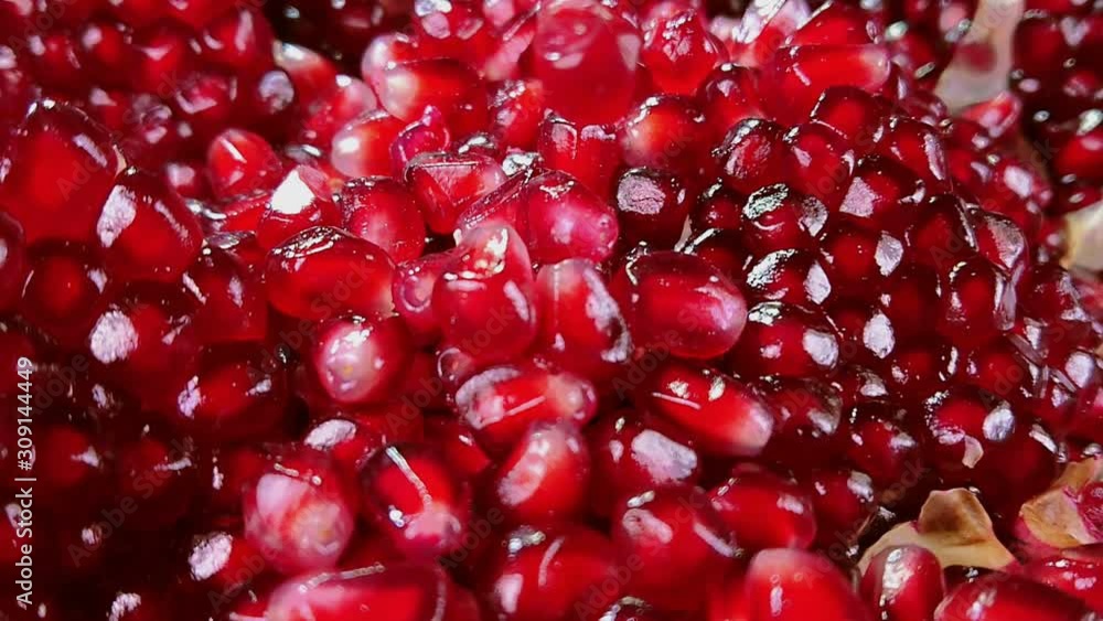 Cloce up of a shining juicy grains of red pomegranate are falling down Cloce up of a shining juicy grains of red pomegranate are falling down