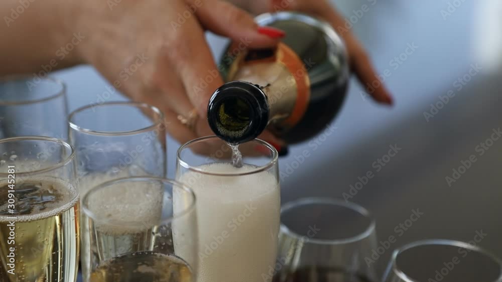 beautiful female hands holding a bottle, pours champagne into the glasses at the wedding ceremony.Slow motion video beautiful female hands holding a bottle, pours champagne into the glasses at the wedding ceremony.Slow motion video