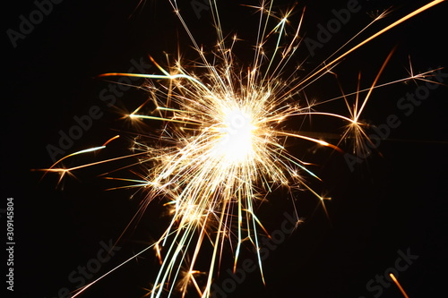 Christmas and New Year s illumination. Burning sparklers scatter bright exploding strips of sparks on a dark background.