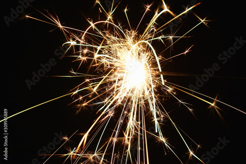 Christmas and New Year s illumination. Burning sparklers scatter bright exploding strips of sparks on a dark background.