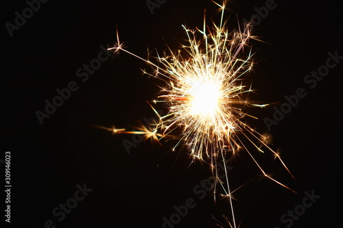 Christmas and New Year s illumination. Burning sparklers scatter bright exploding strips of sparks on a dark background.